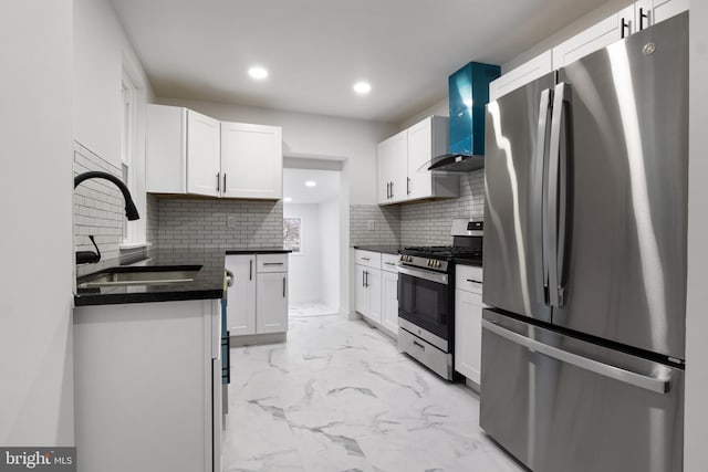 kitchen with appliances with stainless steel finishes, tasteful backsplash, white cabinetry, sink, and wall chimney range hood