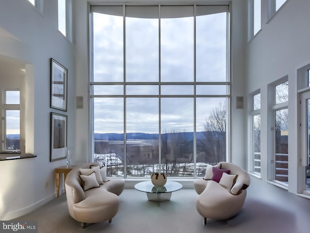 living room with floor to ceiling windows, a mountain view, and a high ceiling