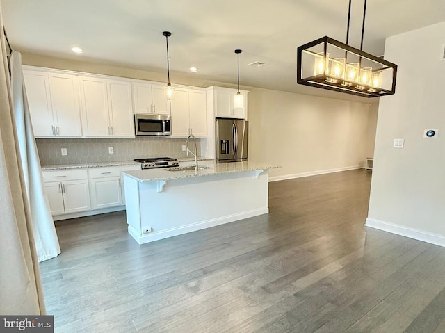 kitchen featuring hanging light fixtures, appliances with stainless steel finishes, a center island with sink, and white cabinets