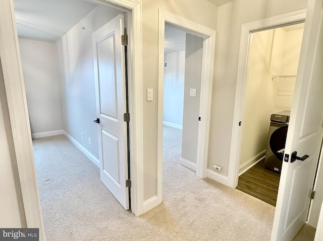 corridor with light carpet and washer / dryer