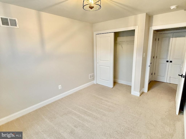 unfurnished bedroom with light colored carpet and a closet