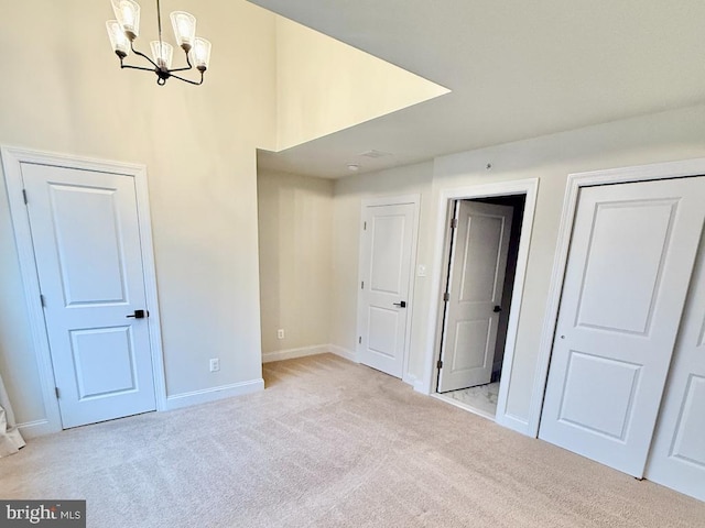 spare room featuring an inviting chandelier and light carpet