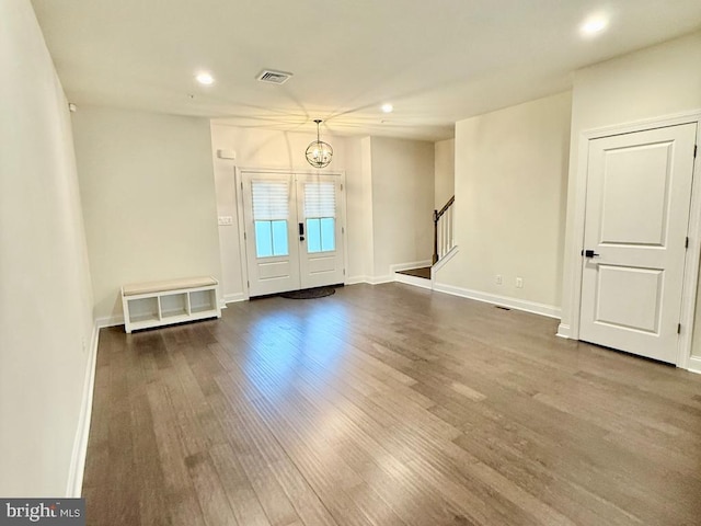 spare room featuring dark wood-type flooring, a chandelier, and french doors