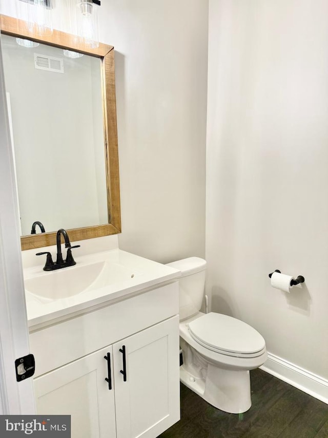 bathroom with hardwood / wood-style flooring, vanity, and toilet