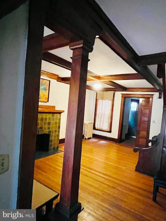 living area featuring a fireplace, radiator, wood finished floors, beamed ceiling, and baseboards