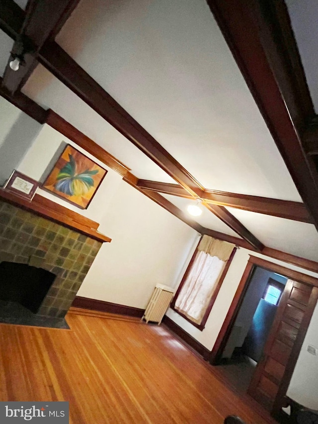 living area with a fireplace with flush hearth, radiator, baseboards, and wood finished floors