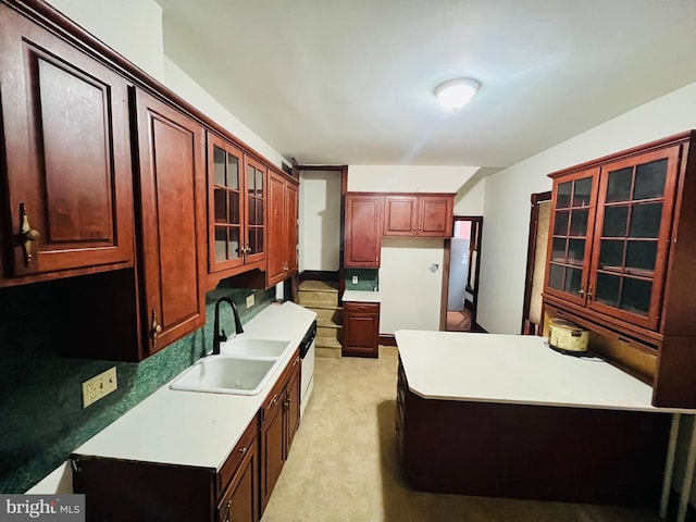 kitchen featuring light carpet, light countertops, a sink, and glass insert cabinets