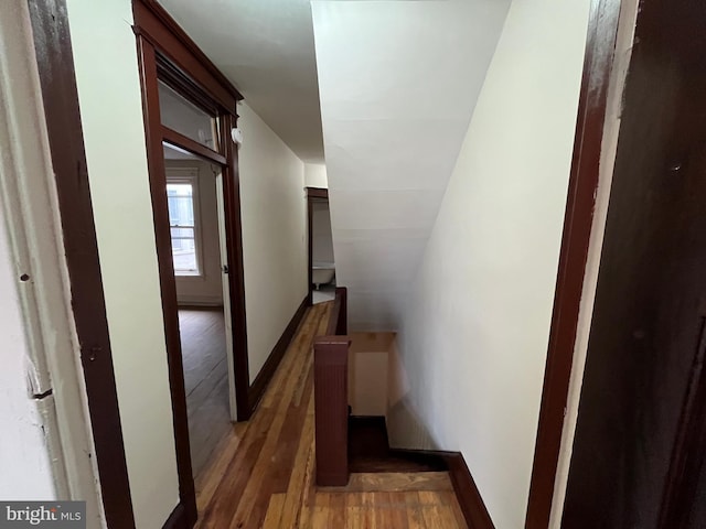 staircase featuring vaulted ceiling, baseboards, and wood finished floors