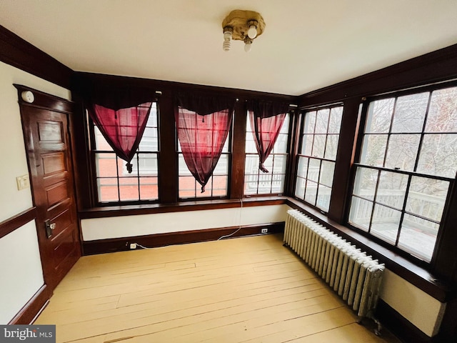 unfurnished sunroom featuring radiator and plenty of natural light