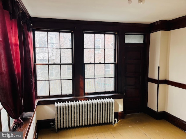 unfurnished room with radiator, light wood-type flooring, and baseboards