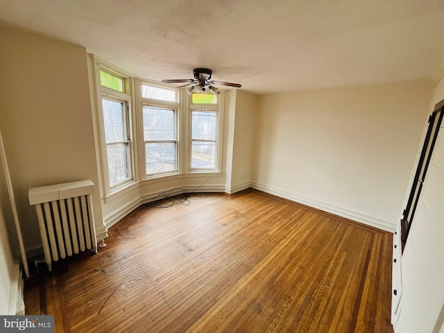 spare room with radiator, wood-type flooring, and baseboards