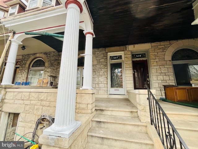 doorway to property with a porch and stone siding