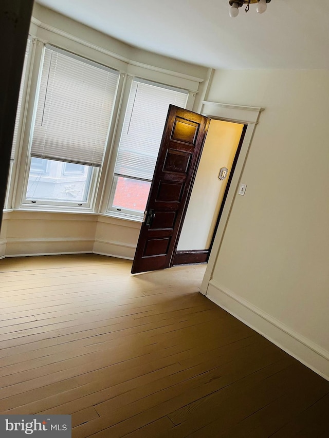 spare room featuring wood-type flooring and baseboards