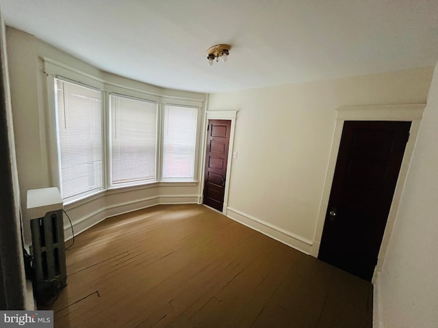 spare room featuring wood-type flooring and baseboards