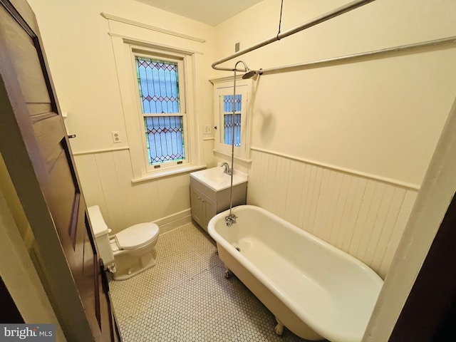 bathroom with a wainscoted wall, a soaking tub, toilet, walk in shower, and tile patterned floors