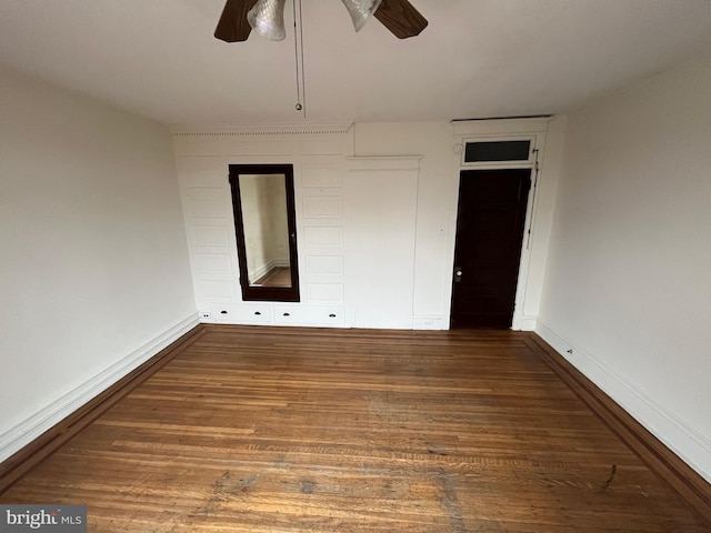 empty room featuring wood finished floors, a ceiling fan, and baseboards