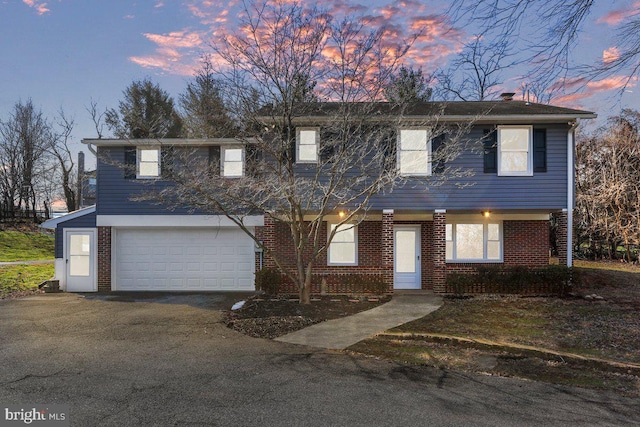 view of front of property with an attached garage, brick siding, and aphalt driveway