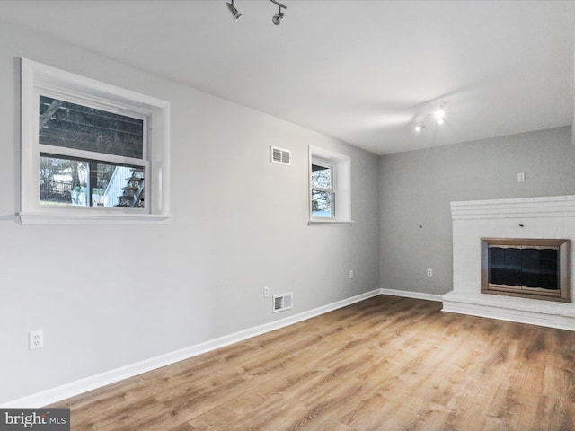 unfurnished living room featuring a fireplace, track lighting, and hardwood / wood-style floors