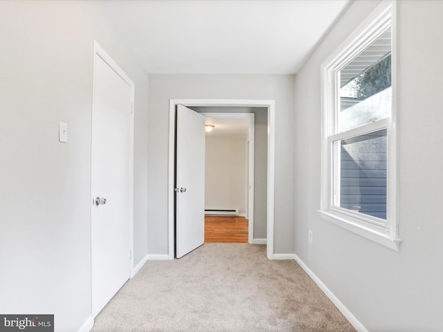 hallway with a baseboard radiator and light carpet