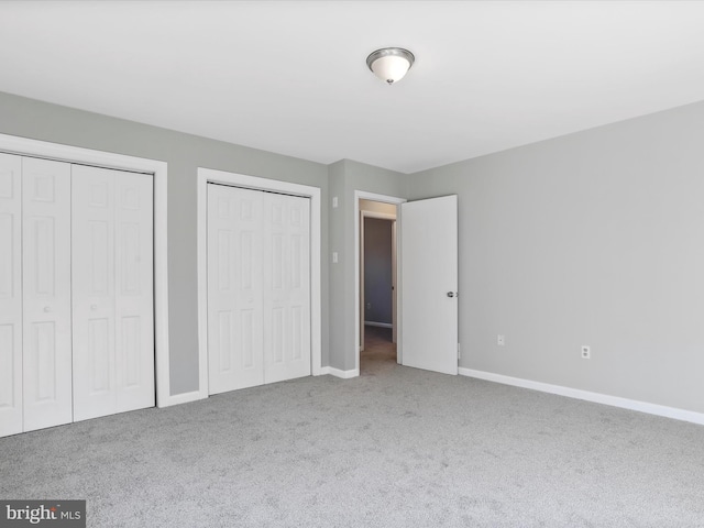 unfurnished bedroom with multiple closets and carpet flooring