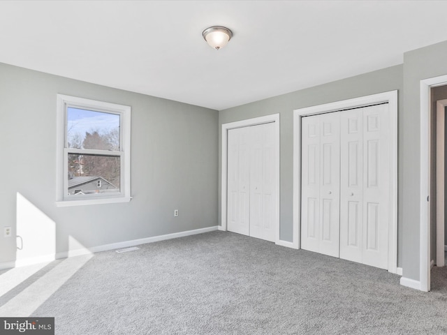 unfurnished bedroom featuring carpet and multiple closets