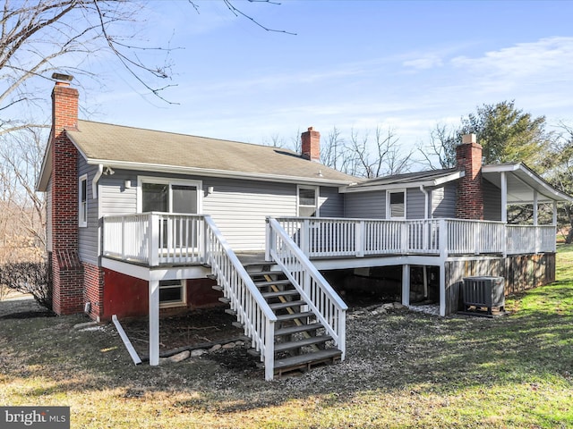 rear view of house with central AC, a wooden deck, and a lawn