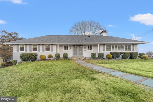 view of front of house with a shingled roof, a chimney, and a front lawn