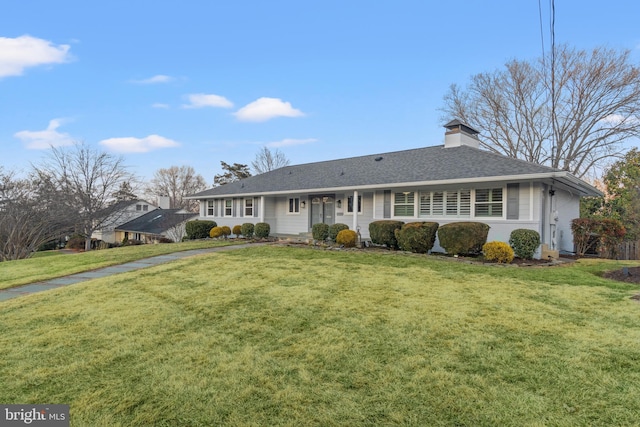 ranch-style home featuring a chimney, a front lawn, and a shingled roof