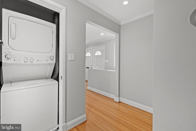 laundry room with baseboards, stacked washer / drying machine, wood finished floors, crown molding, and recessed lighting