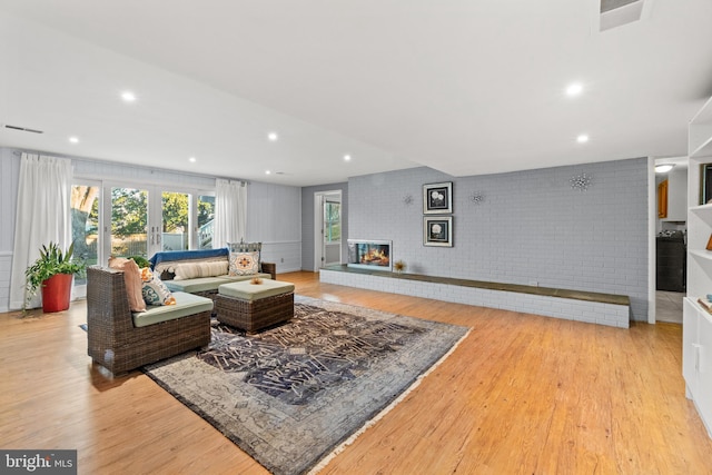 living area with light wood-style flooring, a brick fireplace, visible vents, and recessed lighting