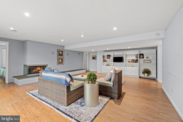 living area featuring light wood-style flooring, a fireplace, and recessed lighting