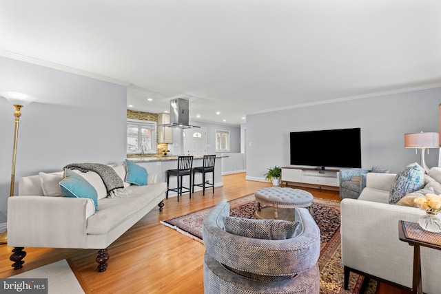 living area featuring baseboards, ornamental molding, recessed lighting, and light wood-style floors