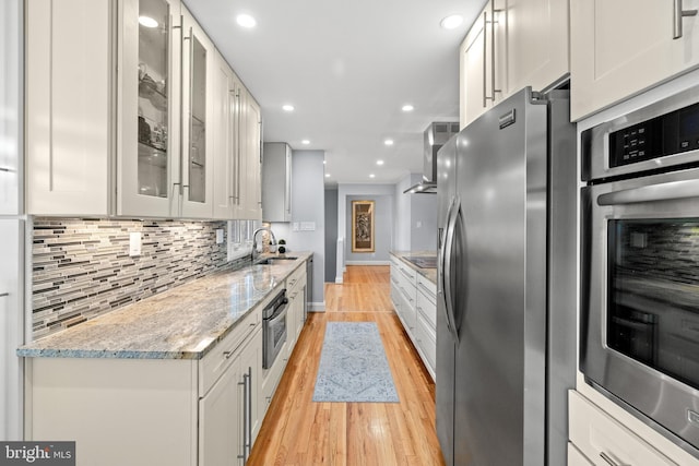 kitchen with light stone countertops, white cabinetry, glass insert cabinets, and stainless steel appliances