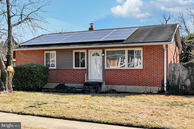 view of front facade with a front yard and solar panels