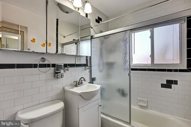 full bathroom featuring shower / bath combination with glass door, tile walls, vanity, decorative backsplash, and toilet