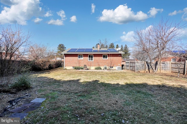 back of house featuring a lawn, solar panels, and central air condition unit