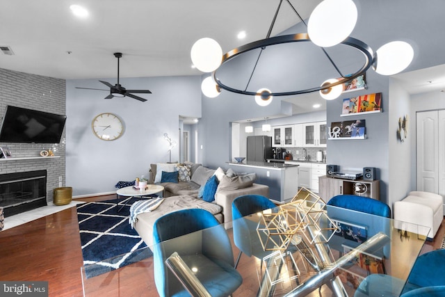 living area featuring visible vents, a fireplace, wood finished floors, high vaulted ceiling, and a ceiling fan