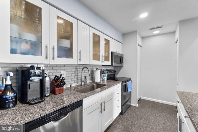 kitchen featuring backsplash, glass insert cabinets, appliances with stainless steel finishes, white cabinets, and a sink