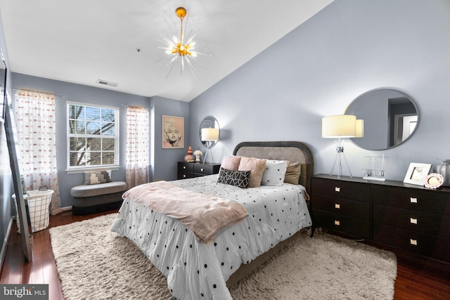 bedroom with visible vents, lofted ceiling, an inviting chandelier, and wood finished floors