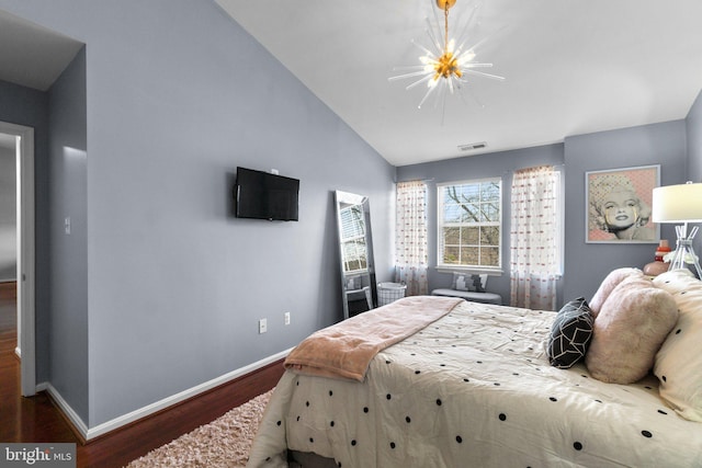 bedroom featuring wood finished floors, visible vents, baseboards, vaulted ceiling, and a chandelier