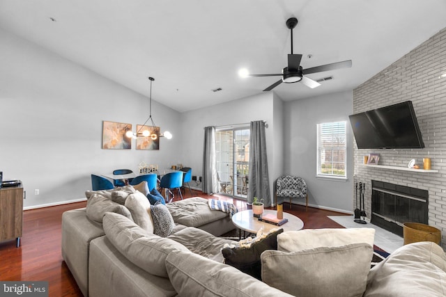 living area featuring lofted ceiling, dark wood-style floors, a fireplace, and visible vents