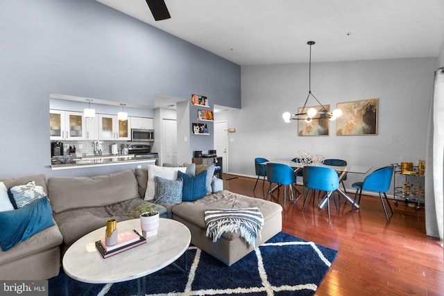 living room featuring baseboards, high vaulted ceiling, an inviting chandelier, and wood finished floors