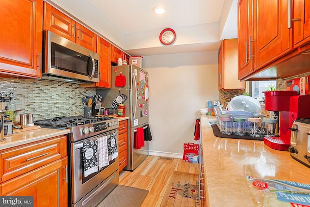 kitchen with stainless steel appliances, backsplash, and light wood-type flooring