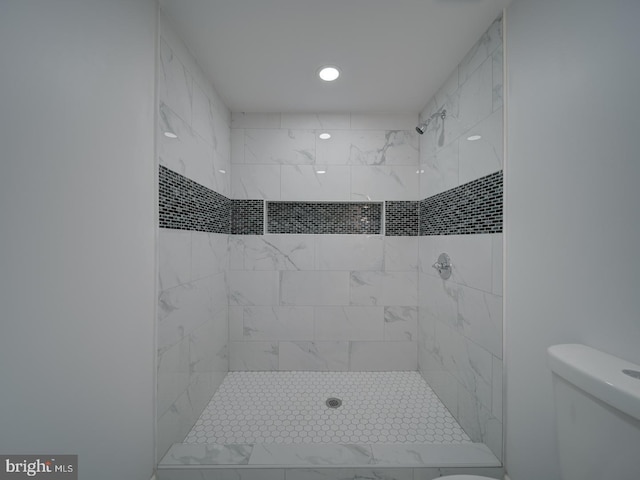 bathroom with tiled shower and toilet