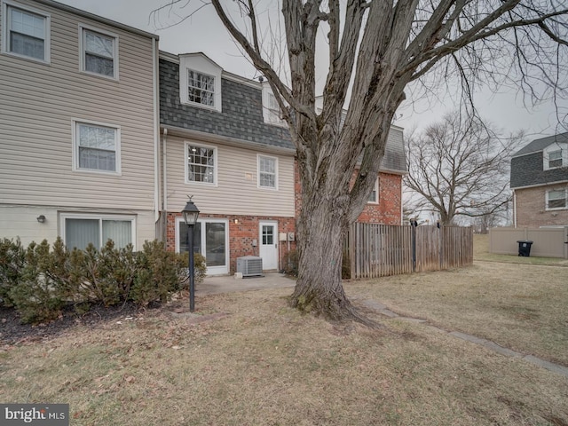 rear view of house featuring a lawn and central air condition unit