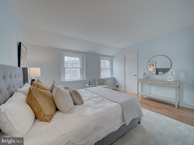 bedroom with vaulted ceiling and light hardwood / wood-style flooring