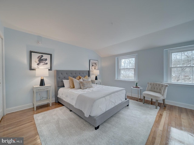 bedroom with lofted ceiling and light wood-type flooring