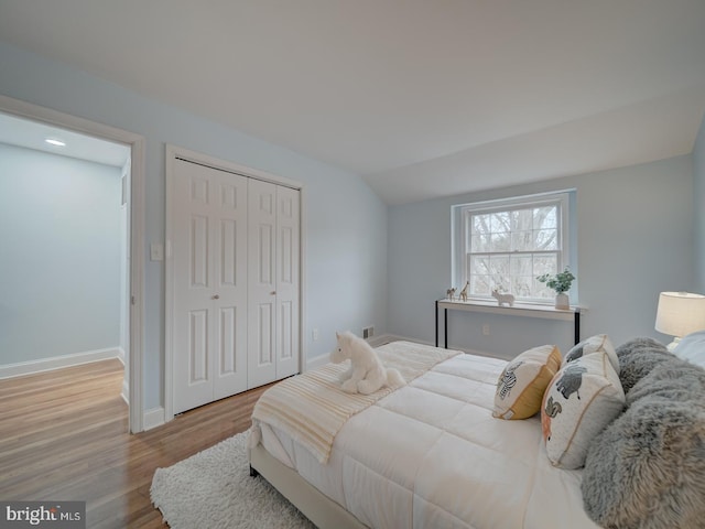 bedroom featuring lofted ceiling, light hardwood / wood-style flooring, and a closet