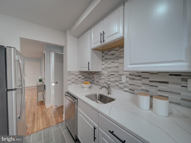 kitchen featuring light stone counters, sink, stainless steel appliances, and white cabinets