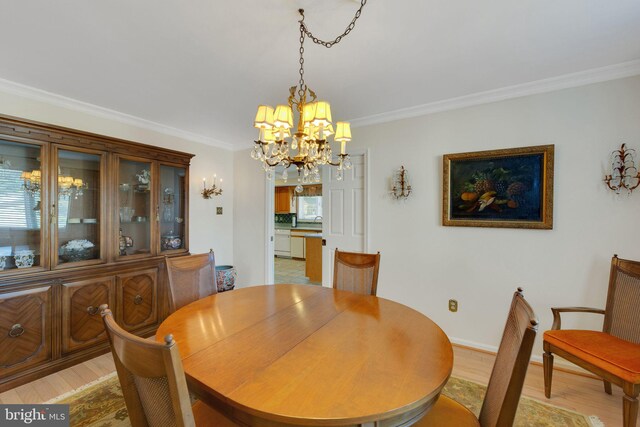 dining space with ornamental molding, sink, a chandelier, and light hardwood / wood-style floors